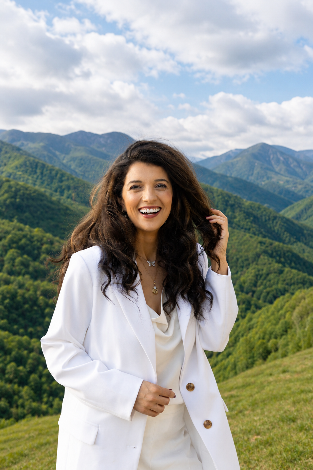 Saloua, the 3 Brains Coach, in a white blazer with the Blue Ridge Mountains behind her